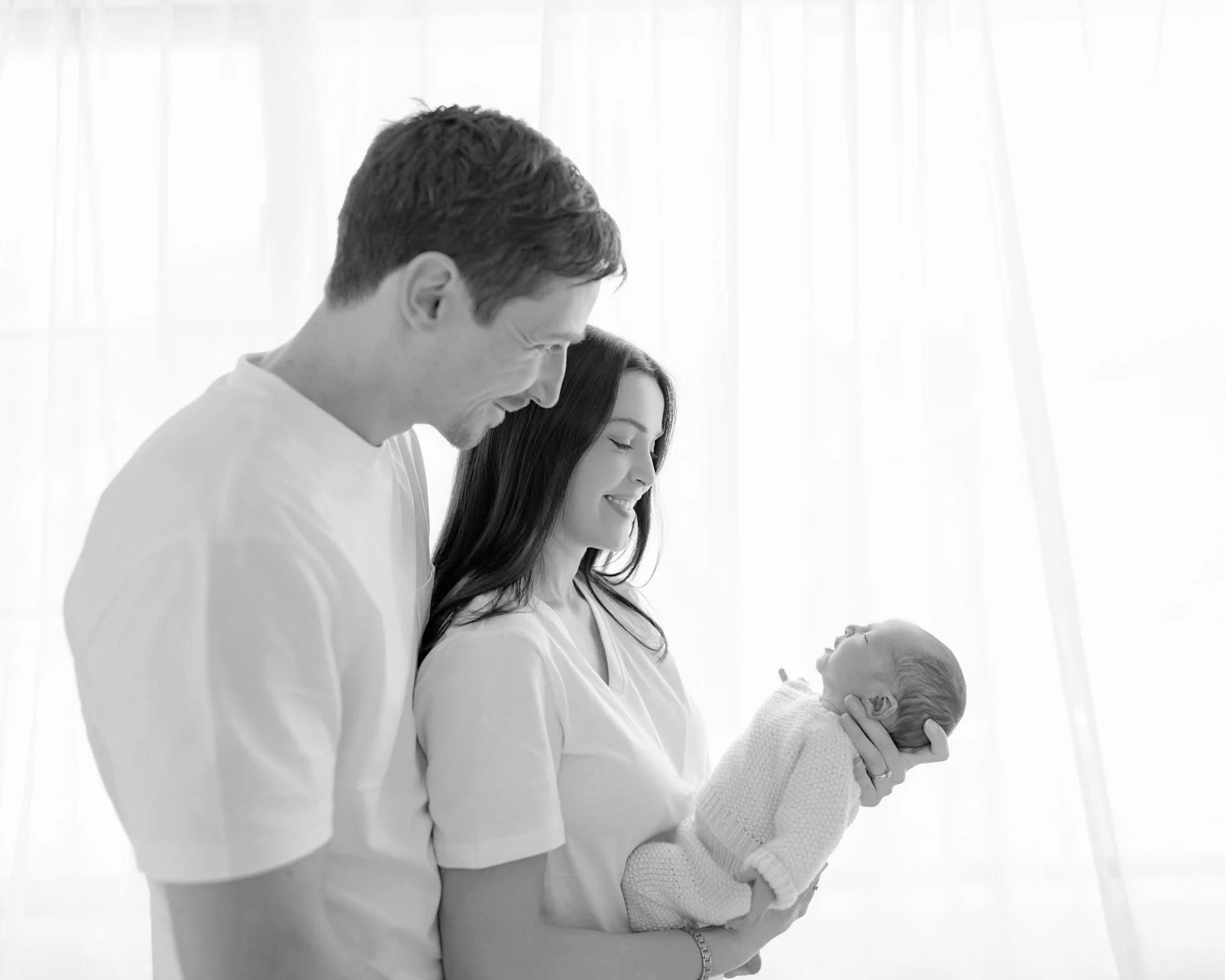 Parents smiling at their newborn baby during a natural guided lifestyle newborn session in Auckland
