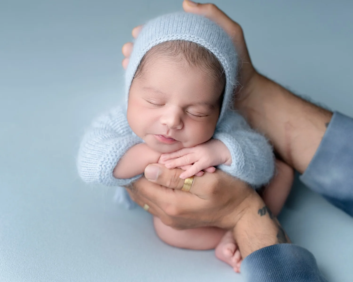 Beautifully posed newborn baby in a soft blue outfit, photographed by Racheal Trail Photography in Auckland