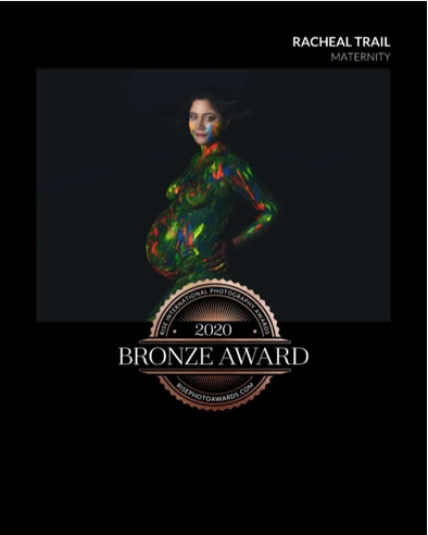 Cover of Racheal Trail Maternity photography award book, featuring a pregnant woman with body painted in vibrant colors, against a black background, with a bronze award badge from 2020.