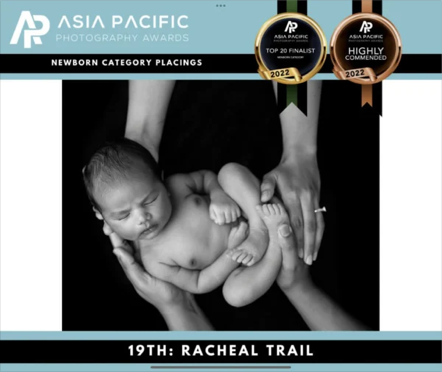 Black and white photo of a newborn baby being held gently by hands, awarded at the Asia Pacific Photography Awards for newborn category, Racheal Trail.