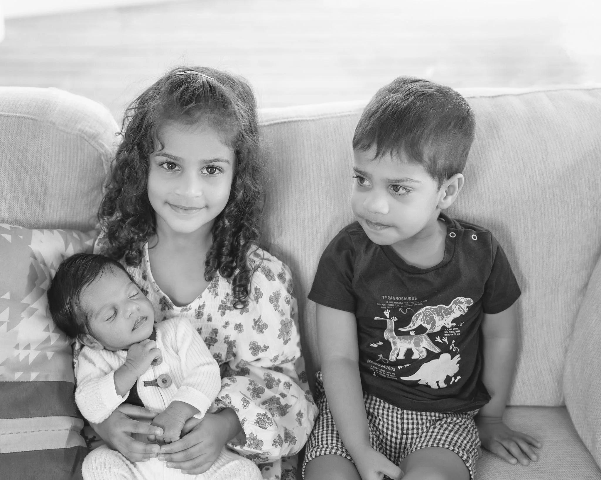 Three siblings together with their newborn baby during a relaxed in-home newborn photography session in Auckland.
