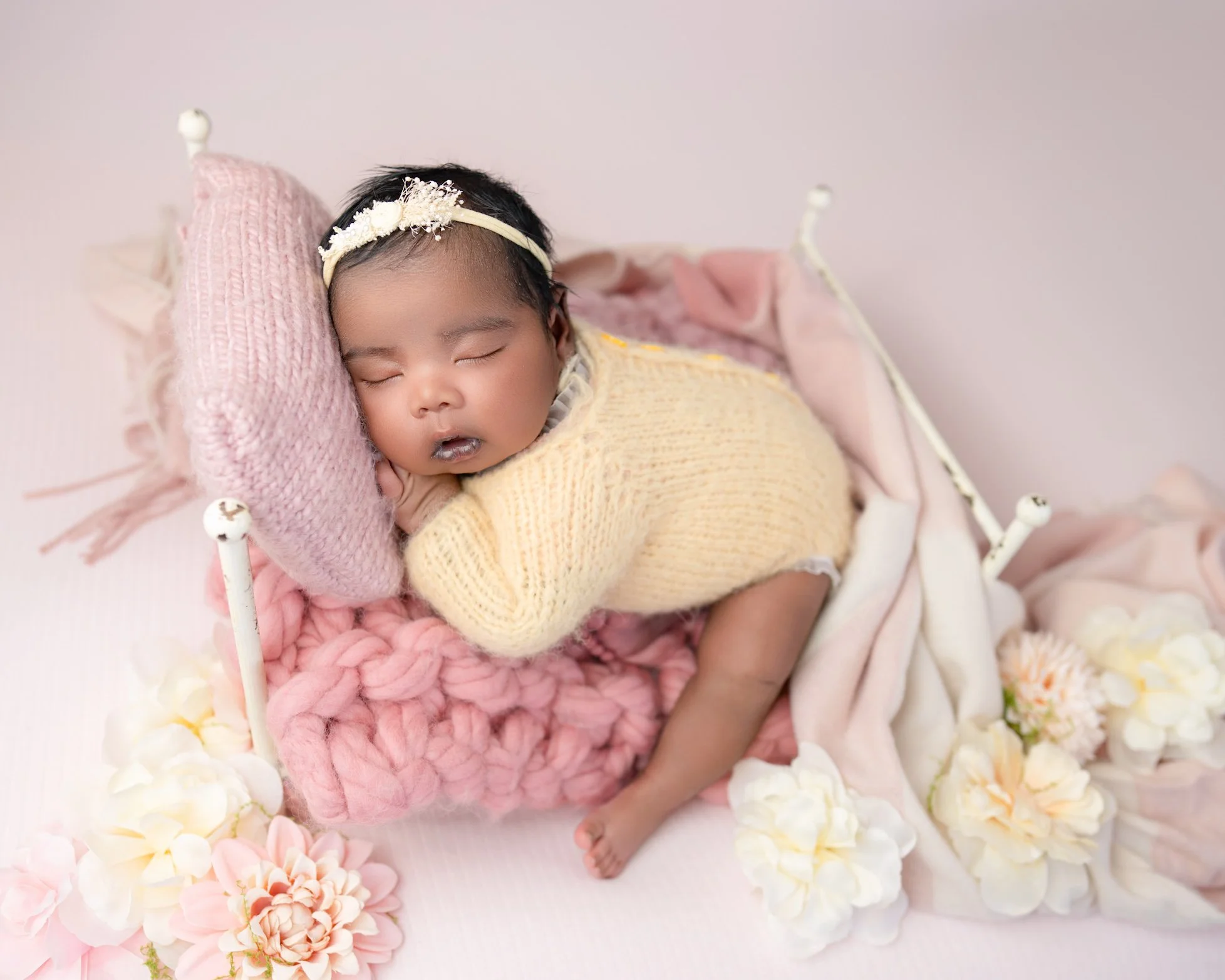 Newborn baby in yellow outfit during a posed newborn photography session in Auckland
