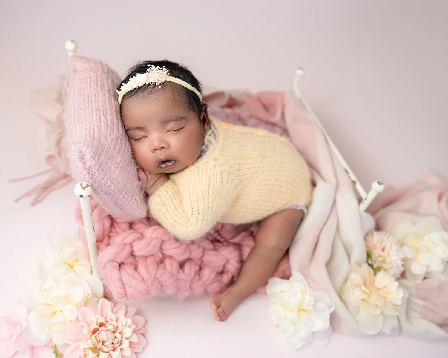 Newborn baby girl posed on a pink bed during an Auckland newborn photography session