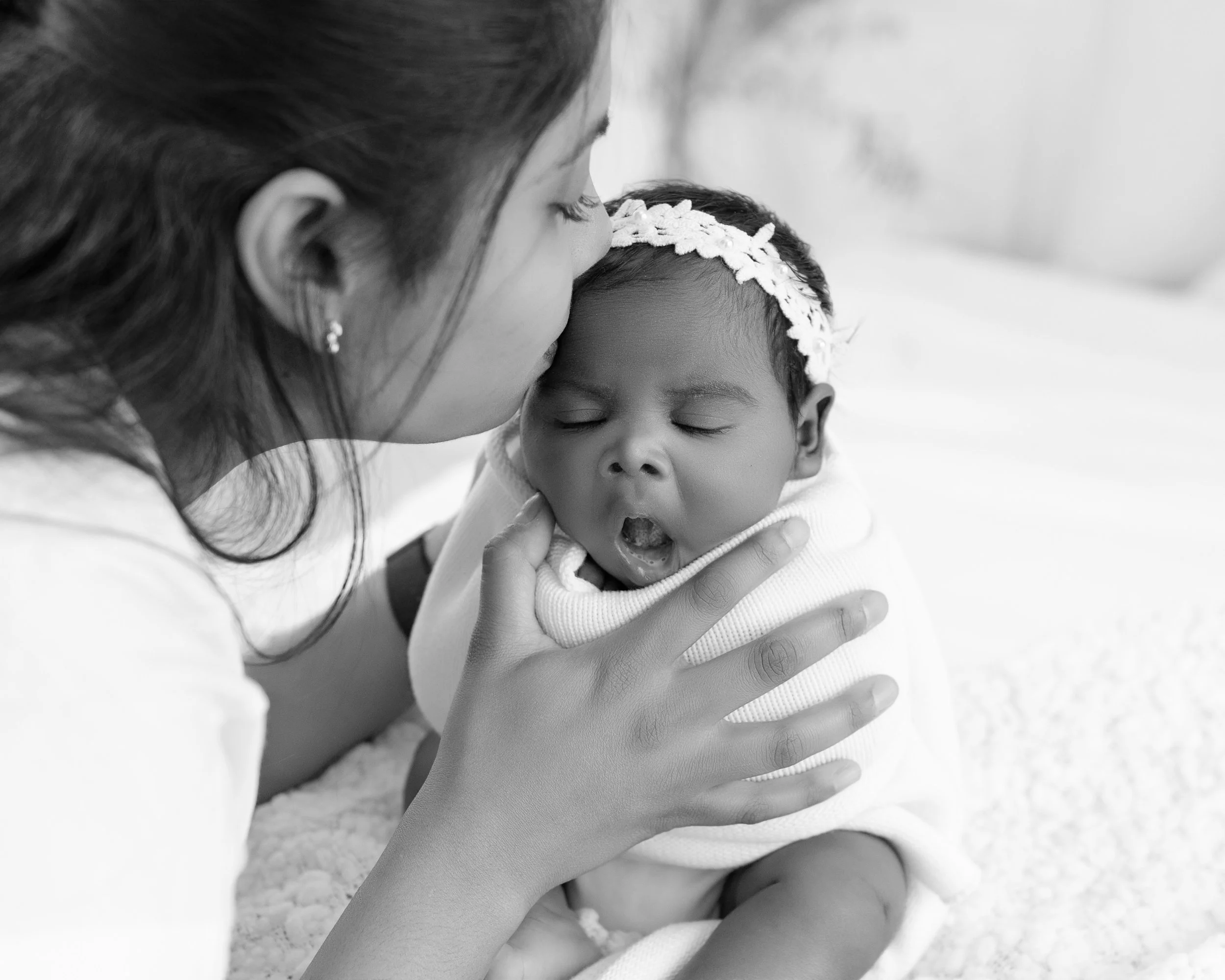 Proud mum tenderly holding her newborn baby for family portraits at a South Auckland studio following a split newborn session.