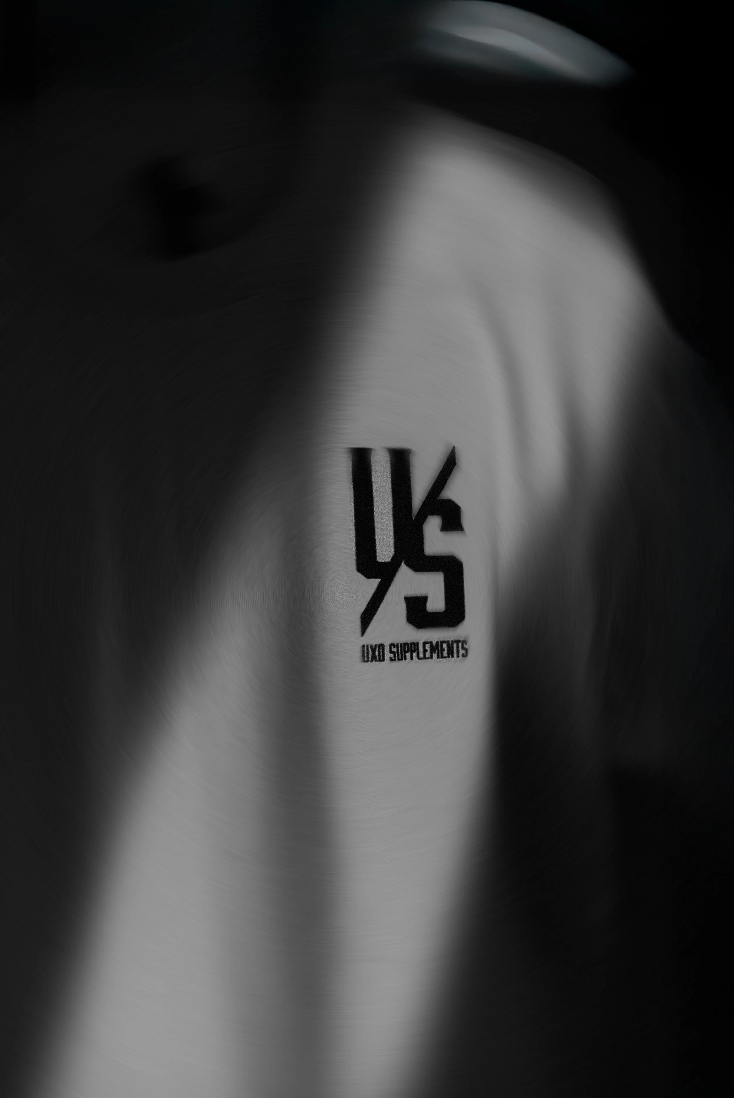 A black and white image UXO SUPPLEMENTS' in the center, with motion blur around the edges.