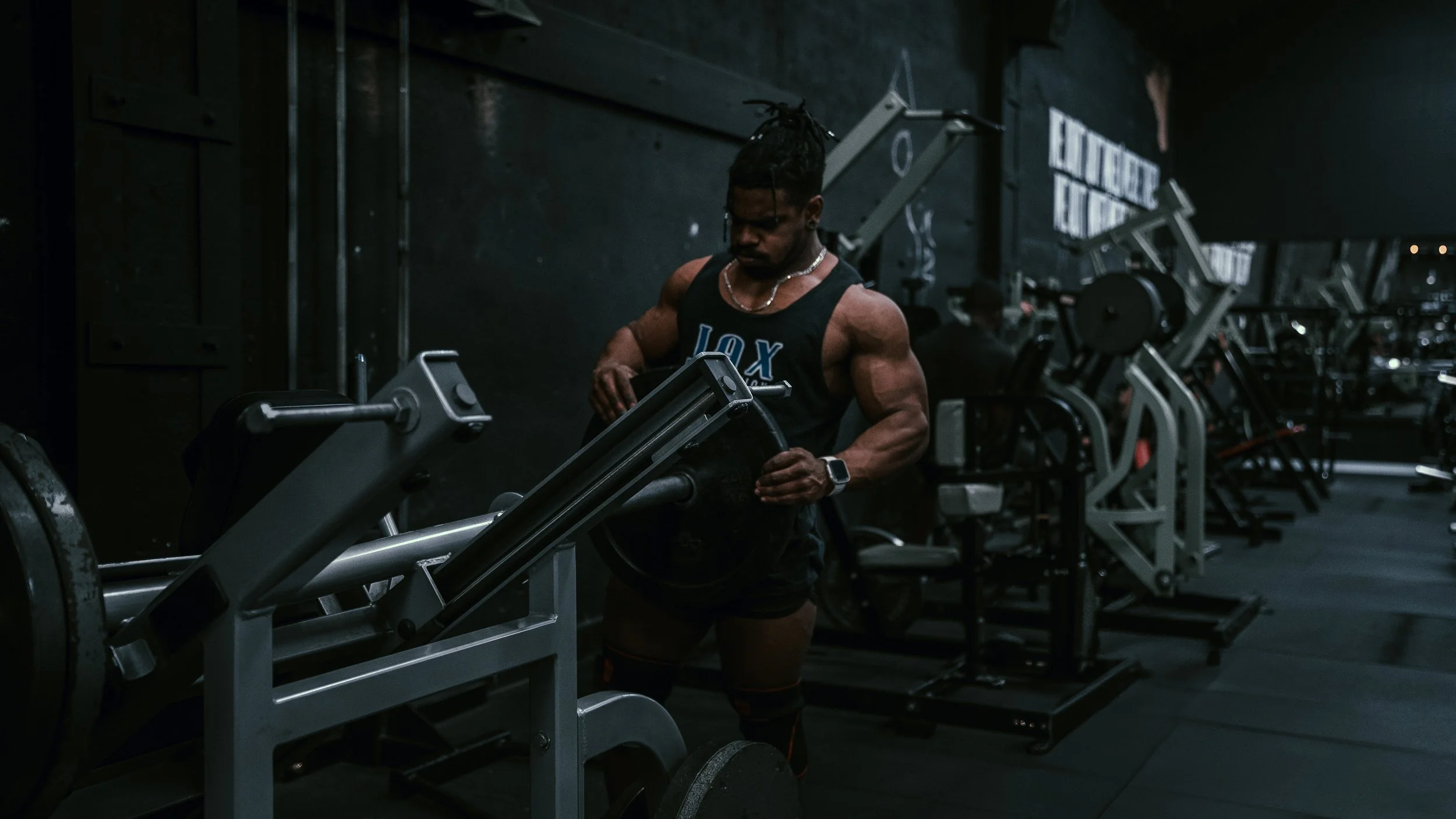A muscular man lifting weights in a dark gym.
