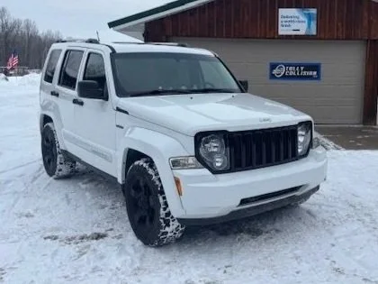 White Jeep Patriot parked in snowy area outside a building with a sign that reads Call & Lightning.