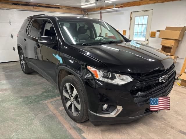 Black Chevrolet Traverse SUV parked in a garage with an American flag cover on the front license plate