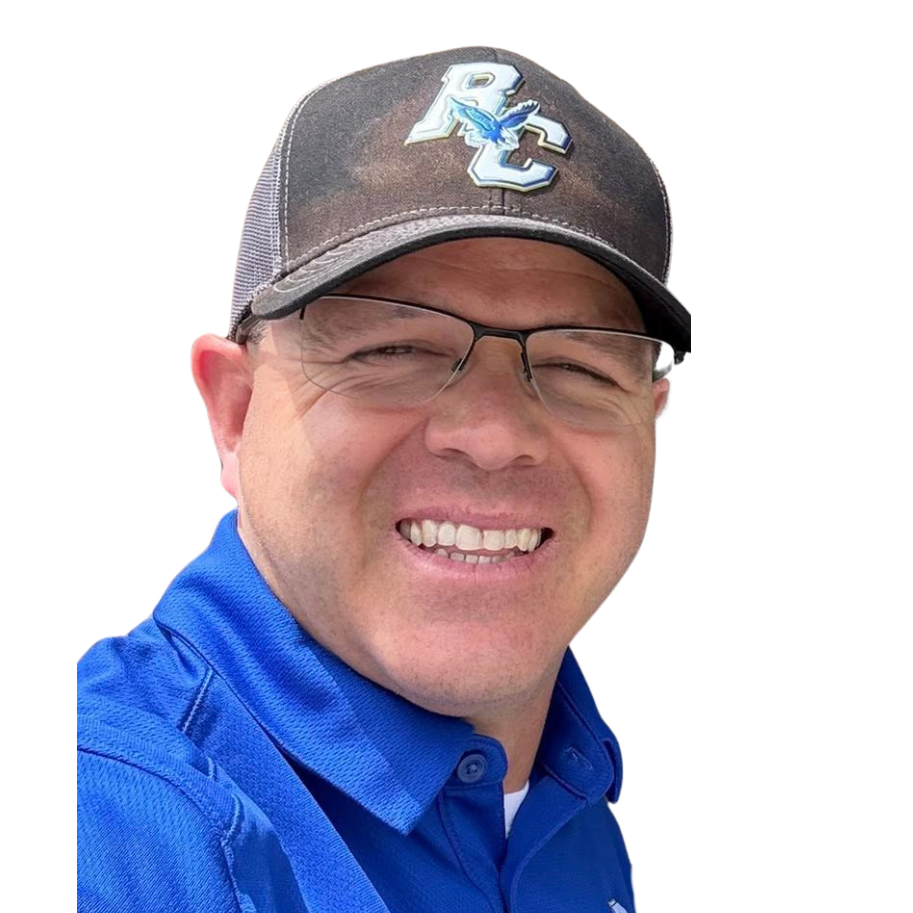 A smiling man wearing glasses, a blue collared shirt, and a black baseball cap with a logo on it.