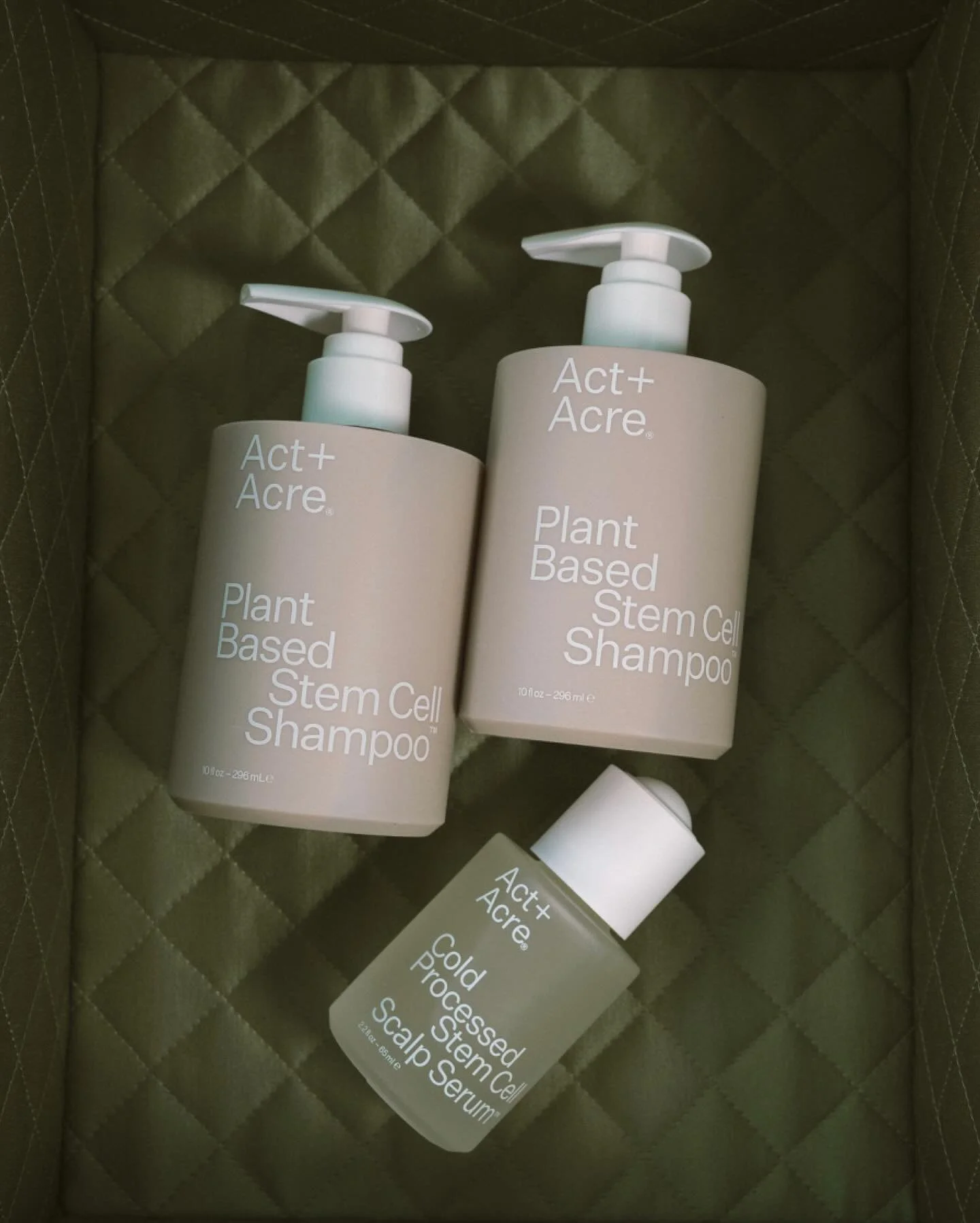 Three bottles of Act+ Acre plant-based stem cell shampoo and scalp serum inside a quilted green box.