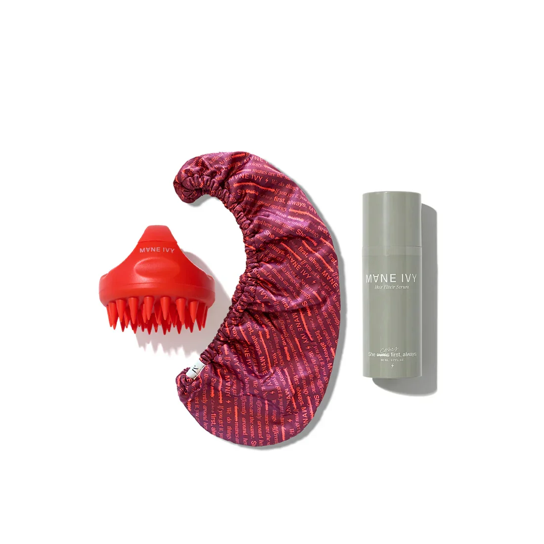 A red massage roller, a satin sleep mask with red text, and a gray bottle of hair elixir serum on a white background.