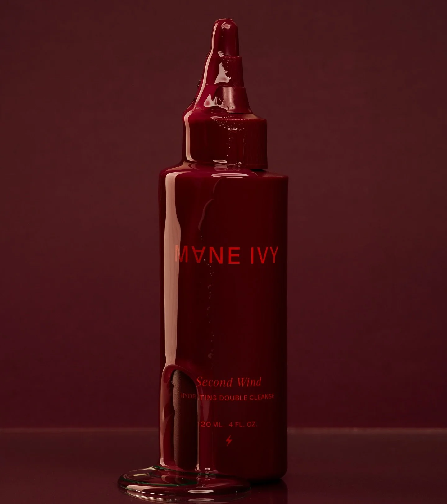 A dark red bottle of hydrating double cleanse called Second Wind with red text and liquid spilling down the front.