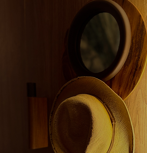 Espelho redondo, chapéu de feltro amarelo e uma garrafa preta sobre uma mesa de madeira