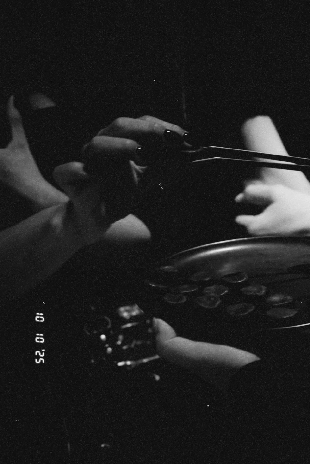 Mãos segurando uma câmera vintage em frente a uma câmera fotográfica tradicional, em uma cena em preto e branco.