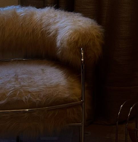 Cadeira com revestimento de pelúcia, ao lado de cortinas de tecido.