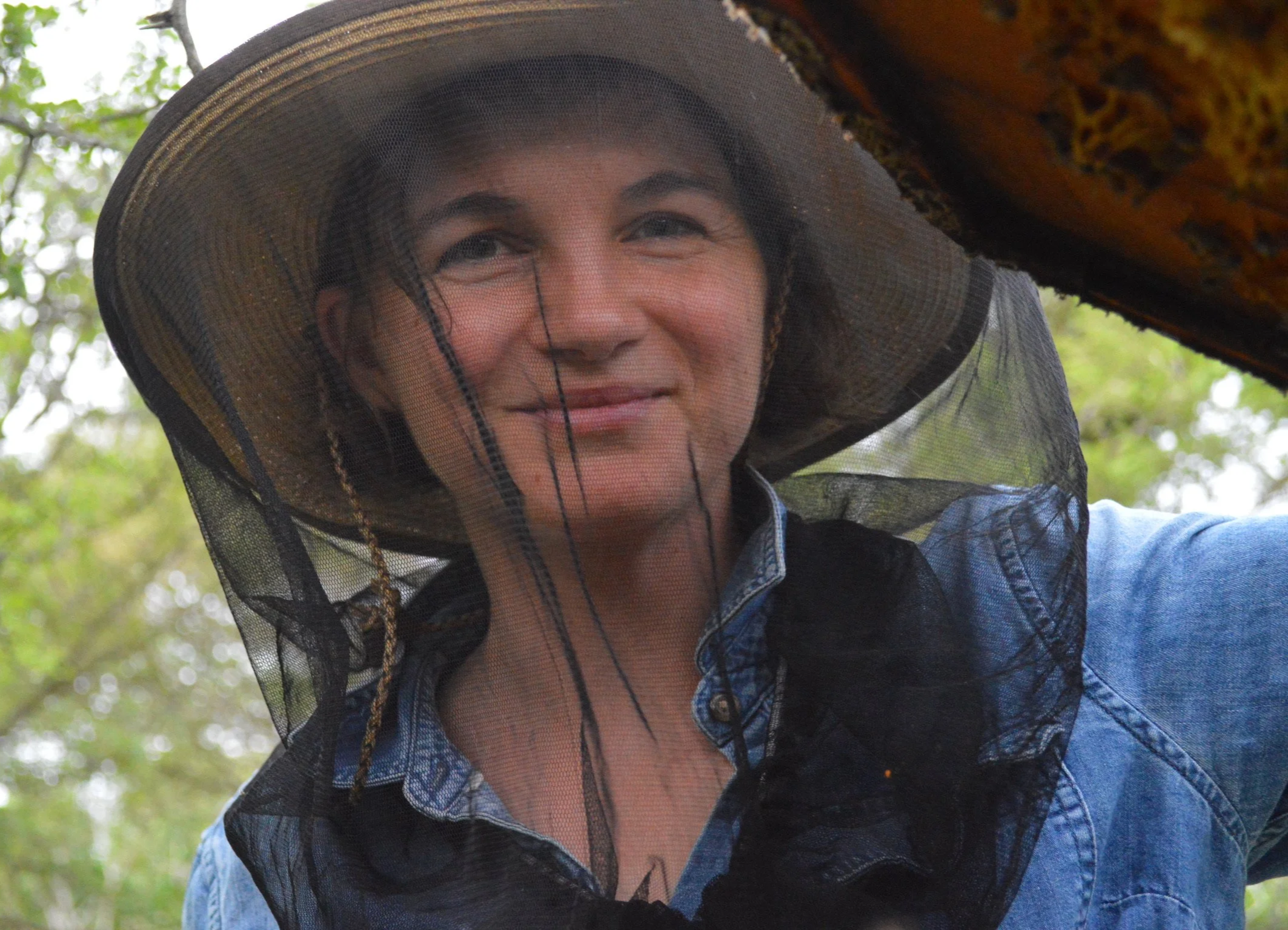 Beekeeper Maggie Shanahan looks at the camera while cracking open a beehive.