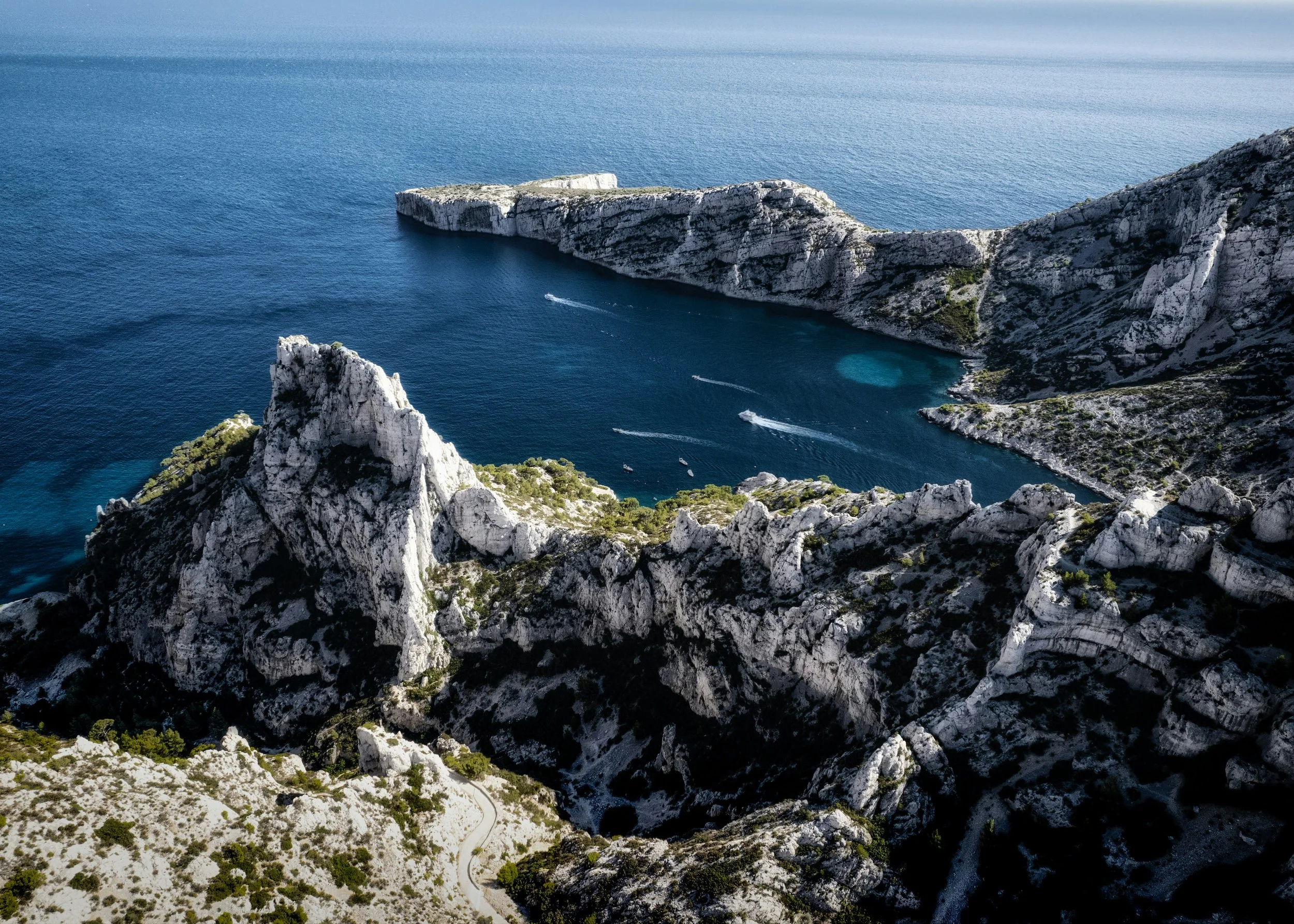 Vue aérienne de falaises blanches et rocheuses au bord de la mer avec des bateaux laissant des traces dans l'eau