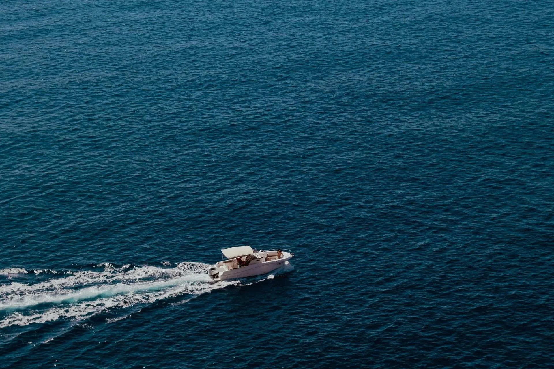 un bateau blanc naviguant sur une mer bleue avec deux personnes à bord