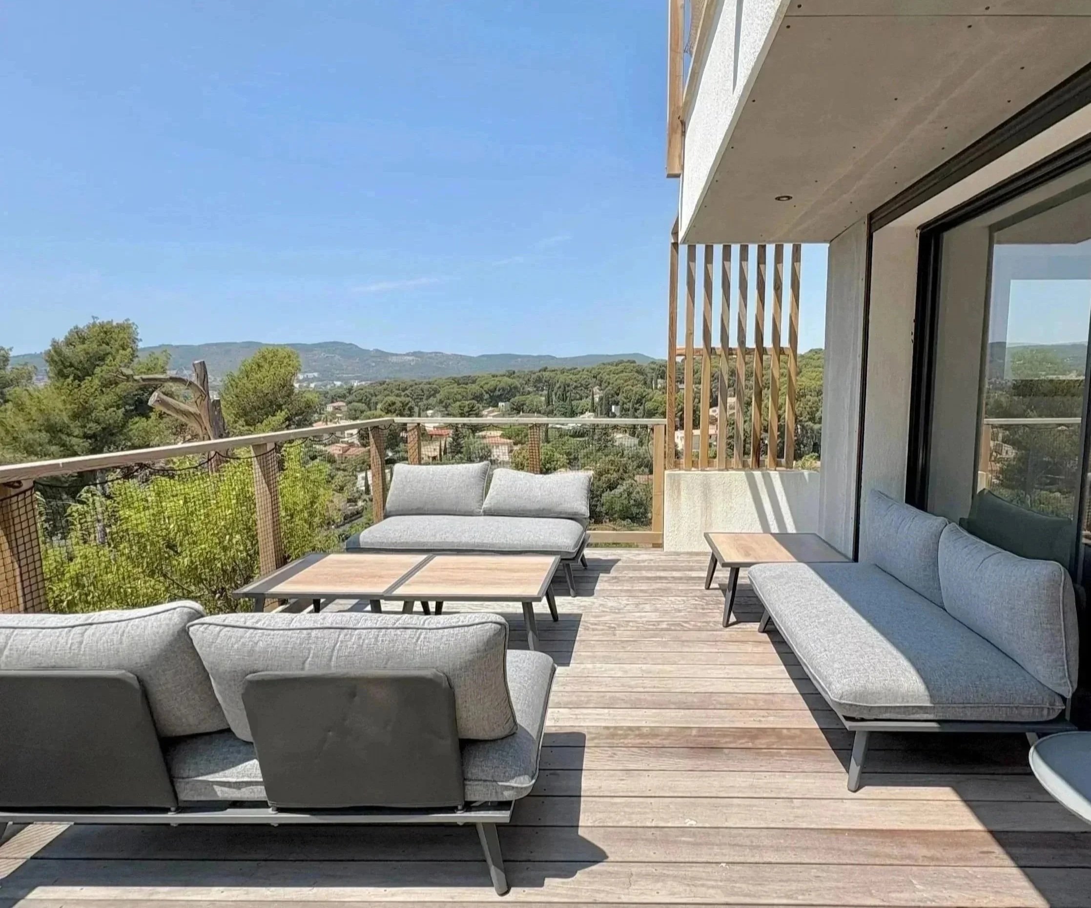 Balcon avec mobilier en extérieur, vue sur la campagne et montagnes en arrière-plan.