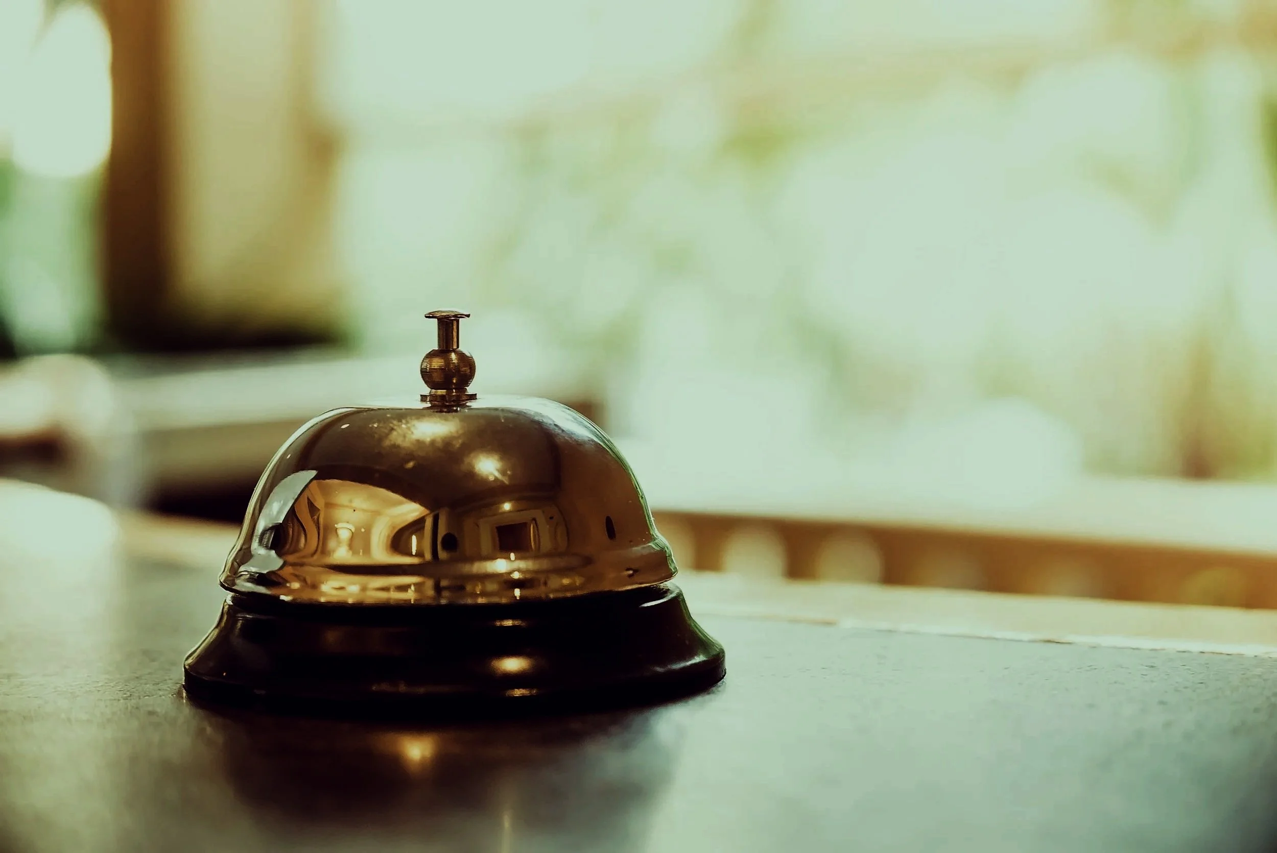 Cloche de service en métal brillant posée sur une surface en bois.