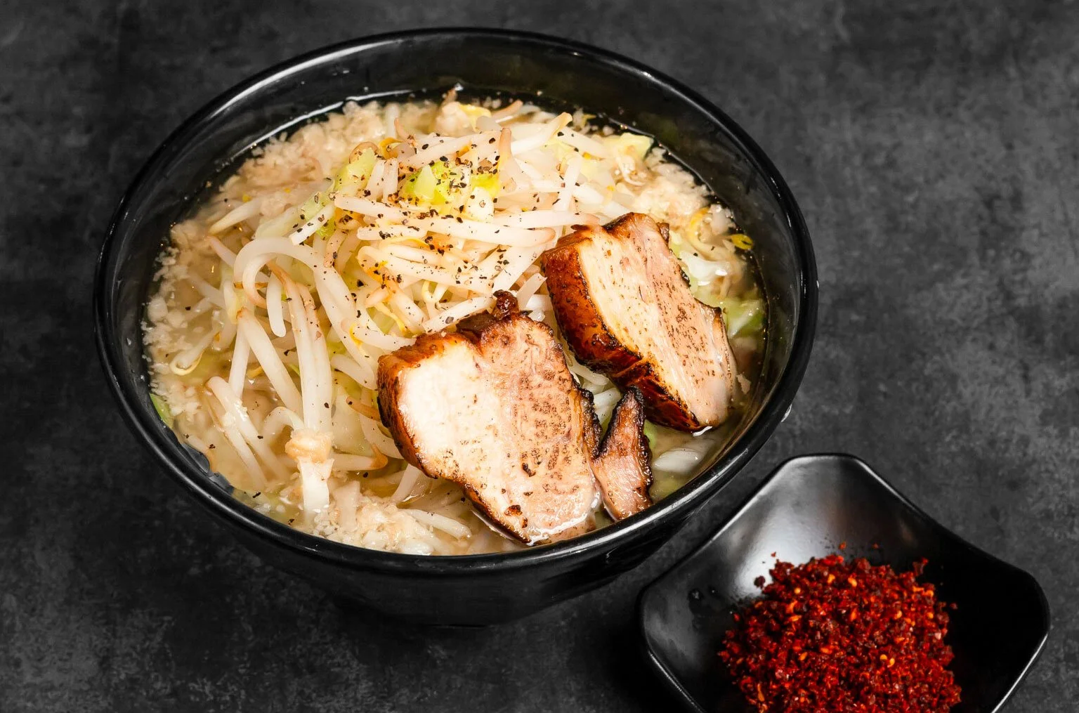 A bold, hearty ramen crafted with our extra thick artisan noodles and rich, savory broth, topped with perfectly torched chashu, crisp vegetables, and a punch of garlic. Served with our homemade chili flakes.