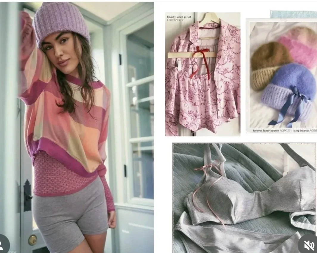 A young woman wearing a pink knit beanie, a multicolored pink, beige, and purple top, and gray shorts, standing indoors near a door.