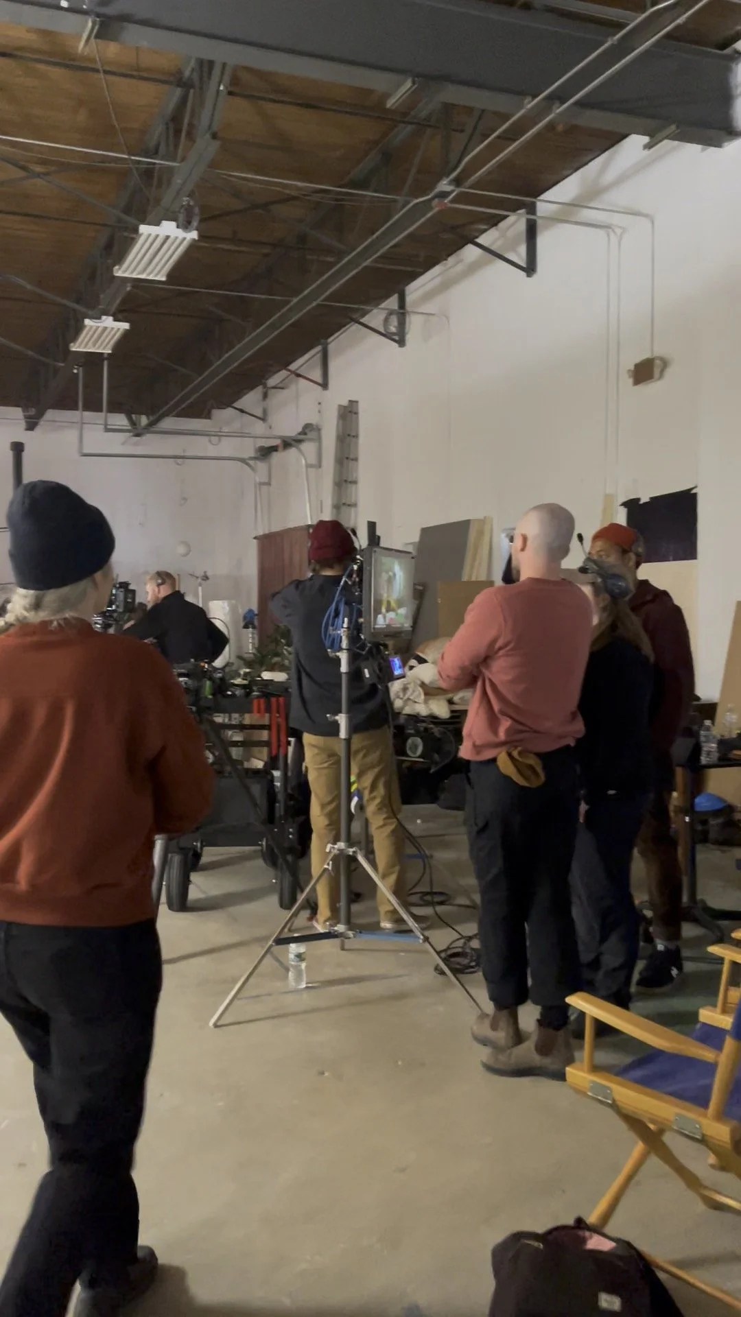 A film or television crew working in a studio with equipment, a monitor, and crew members preparing for a shot.