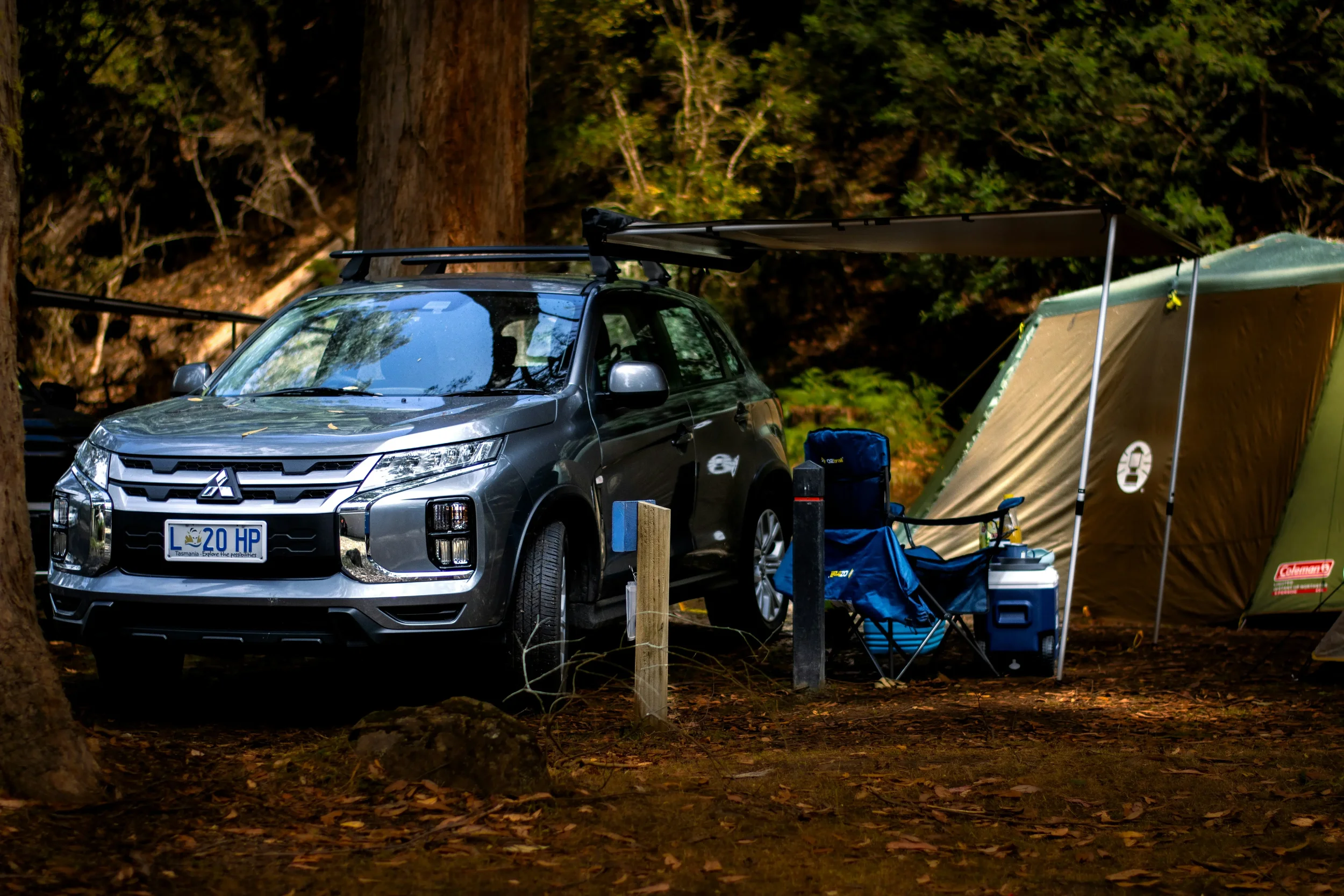 A robust white 4WD vehicle equipped with off-road tires and a roof rack, parked on a dusty red road in the Australian outback under a clear sky.