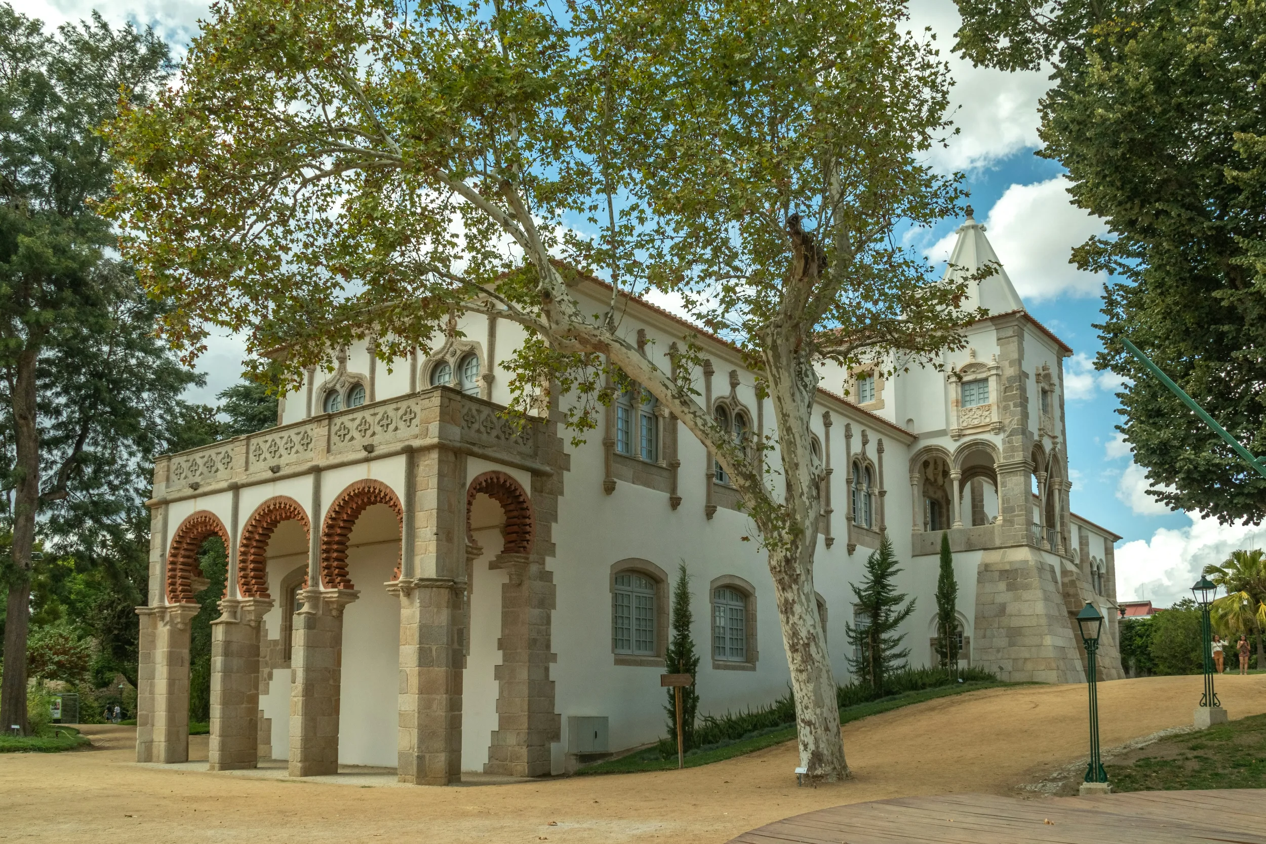 Exterior of the Royal Palace of King Manuel I in Évora, featuring elegant Manueline-style arches and white stone walls surrounded by the lush Public Garden.