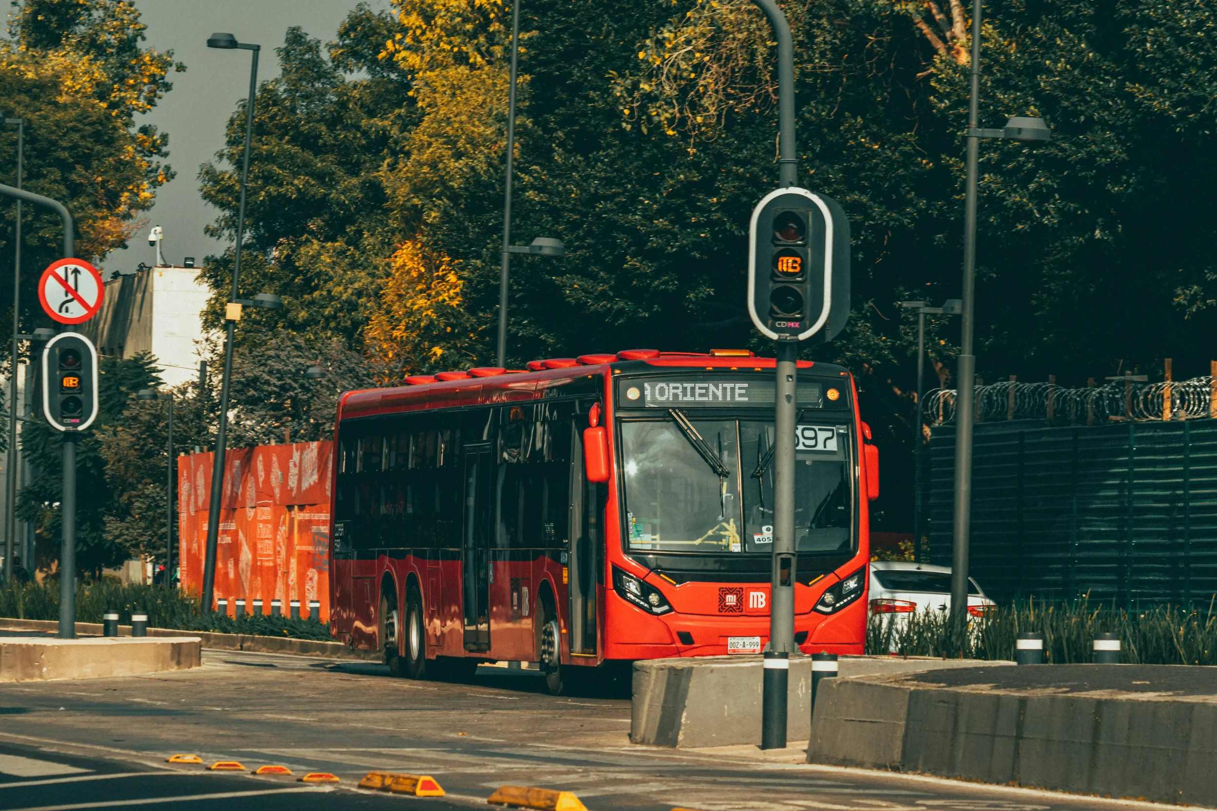 A modern public transportation station in Mexico City showing a red Metrobús bus and urban transit infrastructure.