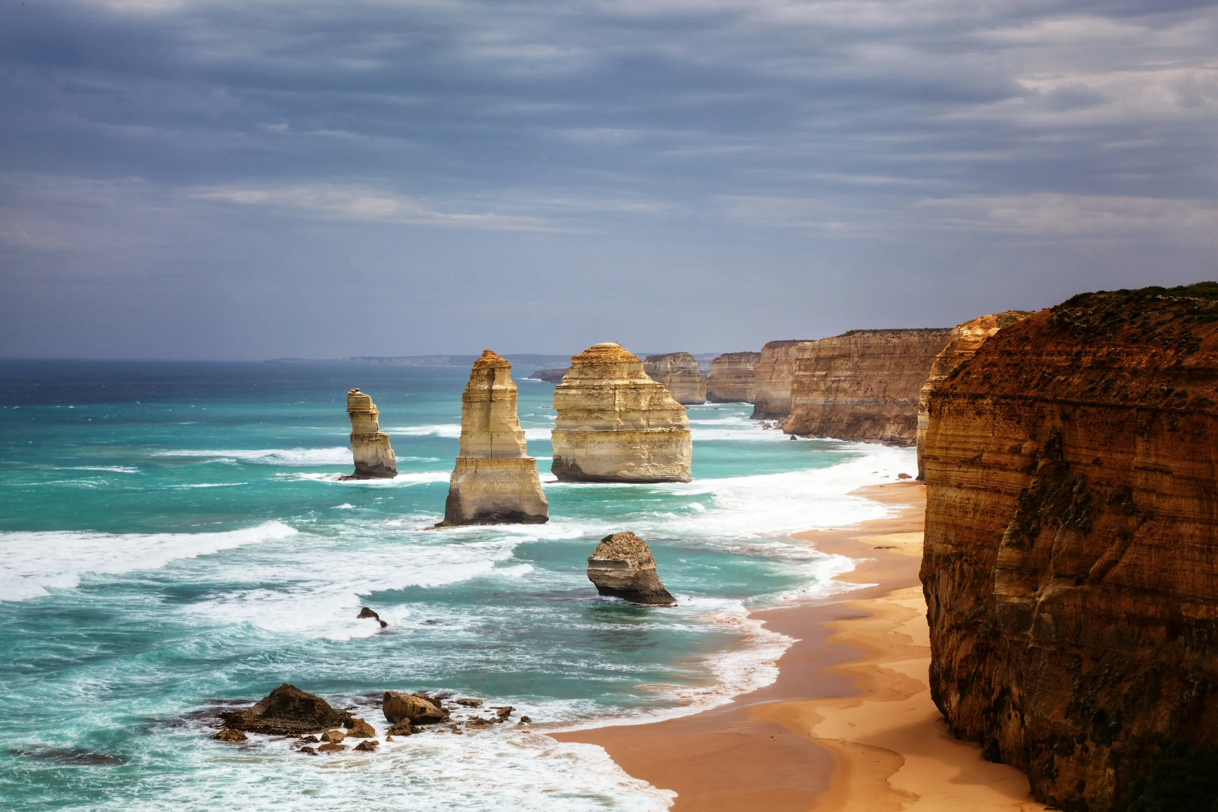 Famous limestone stacks of the Twelve Apostles along the Great Ocean Road coastline in Victoria, Australia, at sunset.