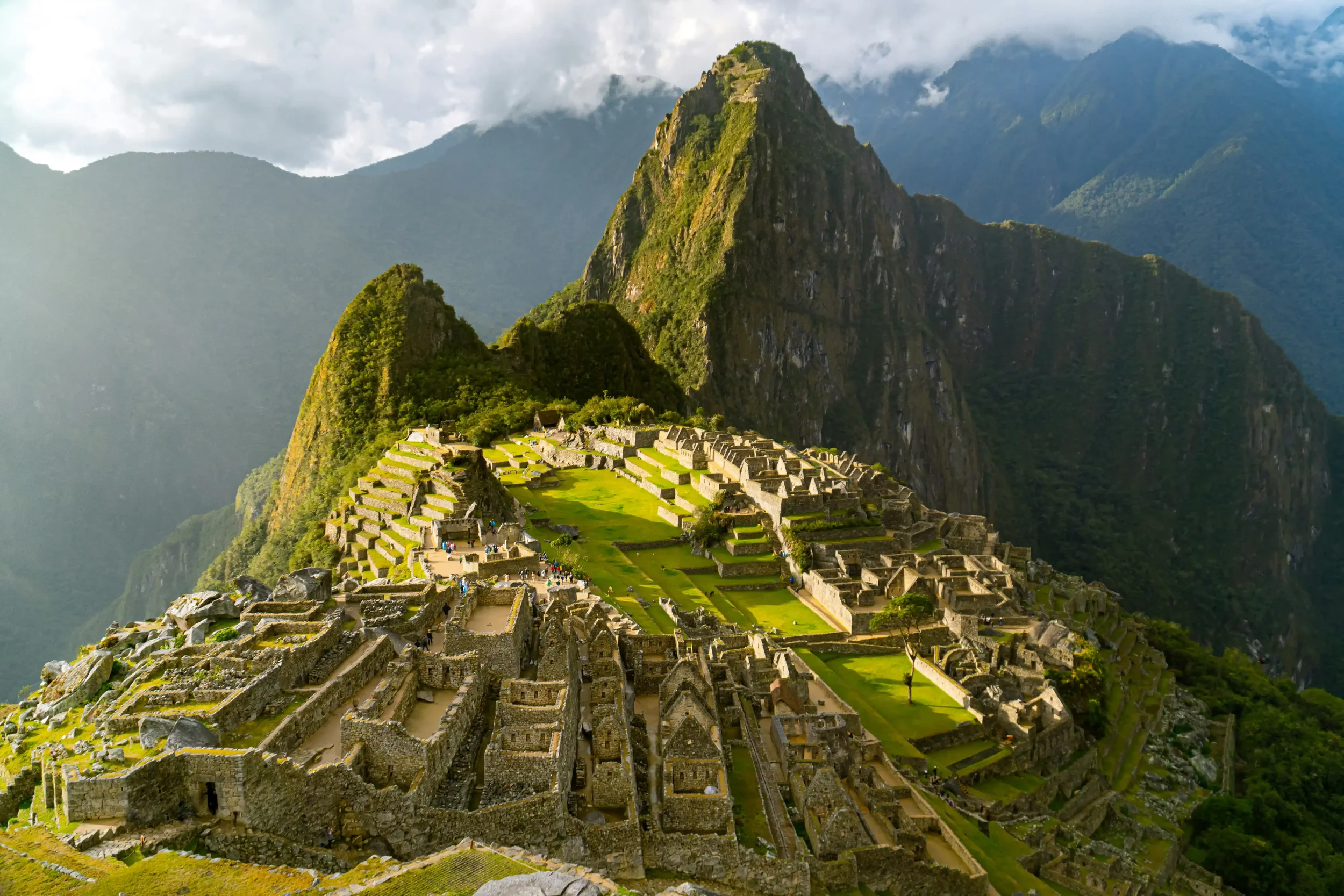 A sweeping, sunlit view of the ancient stone terraces and ruins of Machu Picchu high in the Andes mountains, representing the Heritage Trails historical travel itineraries on Swallow's Notes.