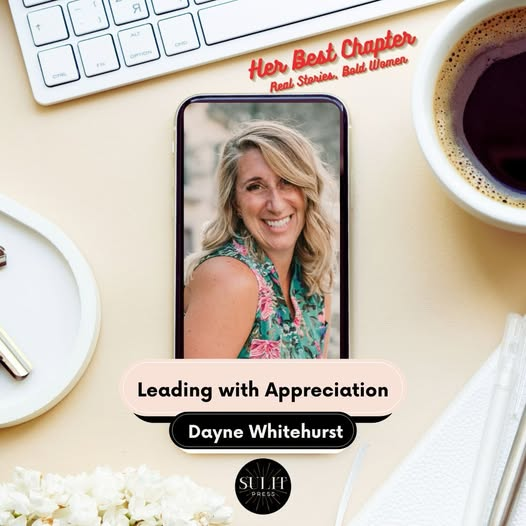 Smartphone on desk displaying a smiling woman with blonde hair and a floral top, surrounded by a keyboard, coffee cup, white plate, white napkin, and white flowers, with text about appreciation and led by Dayne Whitehurst.