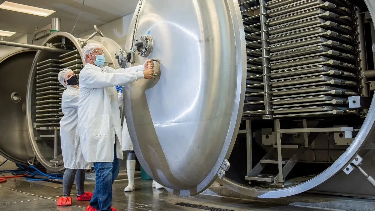 Scientists in lab coats and masks working on large scientific equipment in a laboratory setting. GarageShops.ca