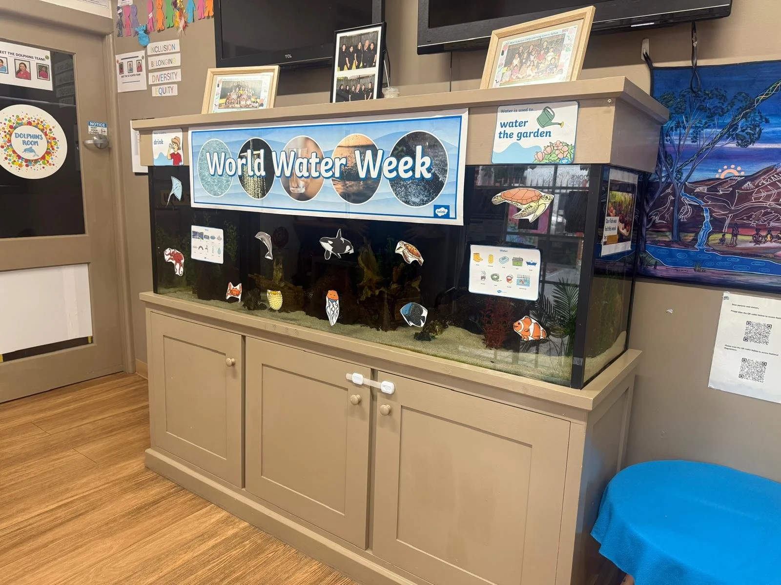 An educational display for World Water Week featuring an aquarium with various fish and aquatic-themed decorations, a banner, and informational signs about water.