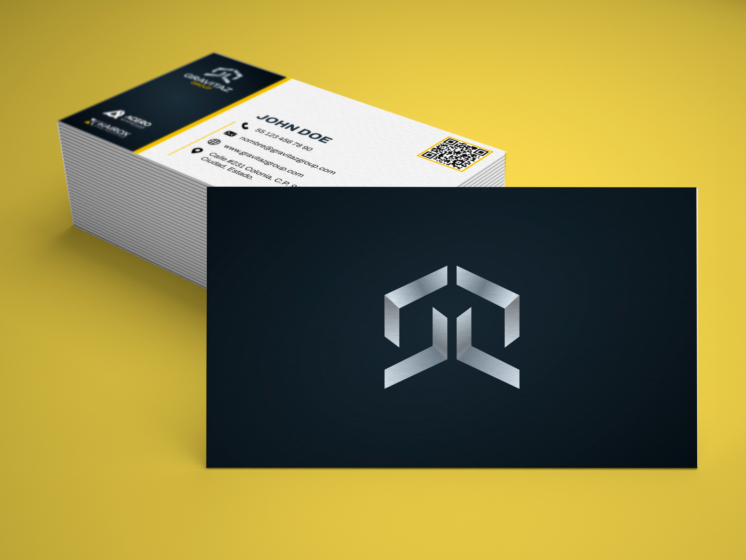A stack of business cards with a black and yellow design, featuring a silver geometric logo on the front and contact information on the back, placed on a yellow surface.