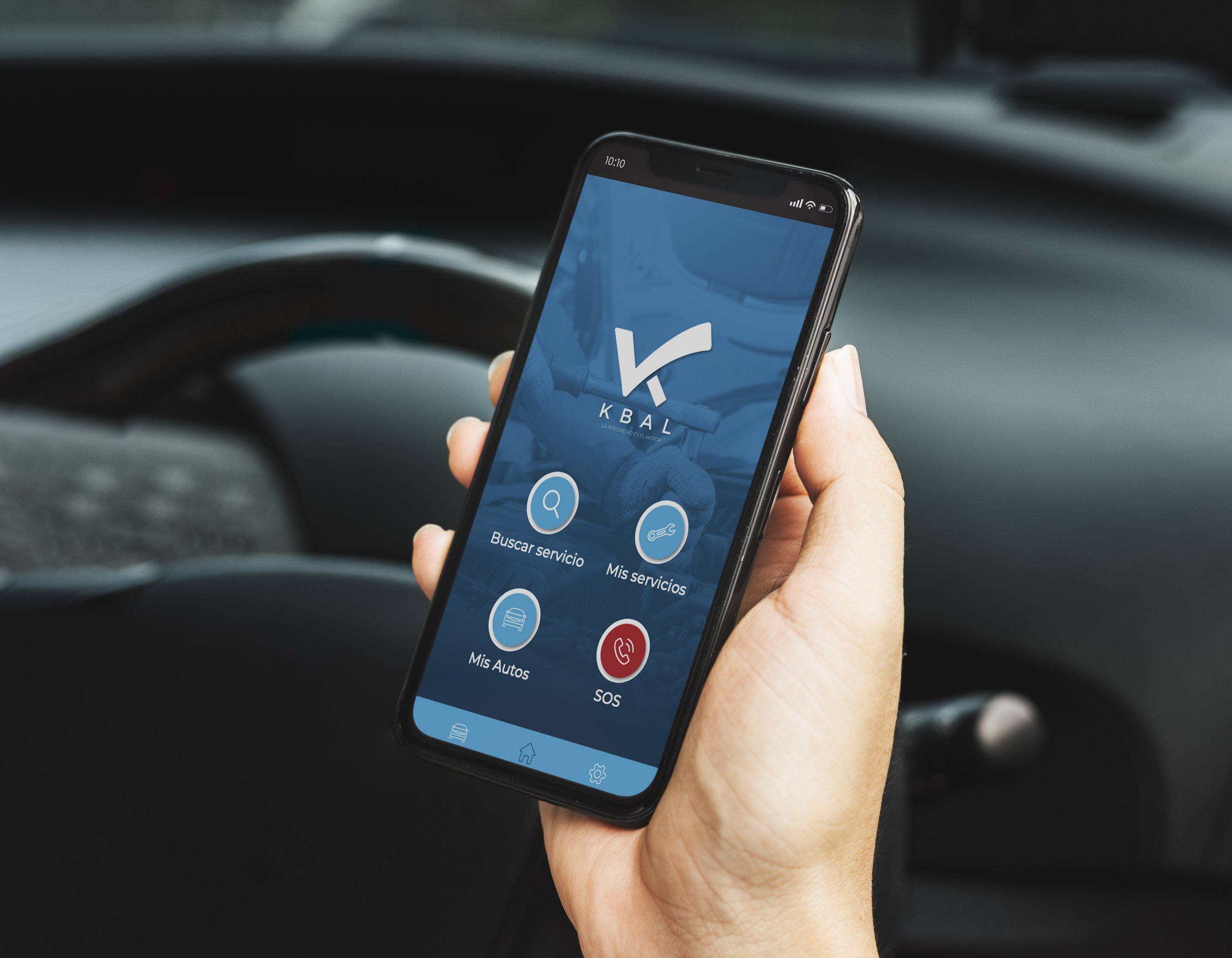 A person holding a smartphone inside a vehicle, displaying a mobile app for Kbal with options for searching services, my services, my cars, and SOS.