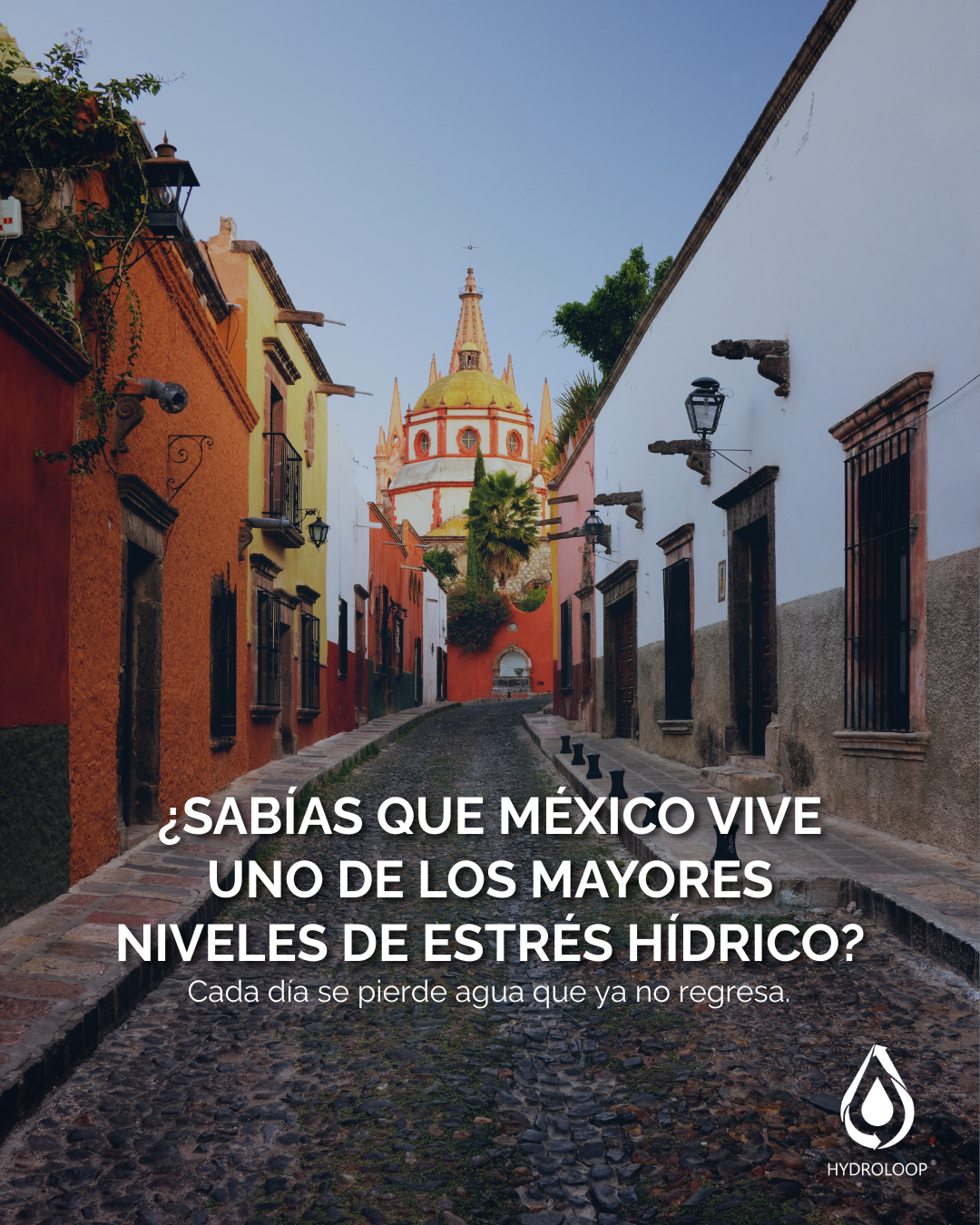 Colored buildings and a church in a narrow cobblestone street in Mexico, with a message about drought.
