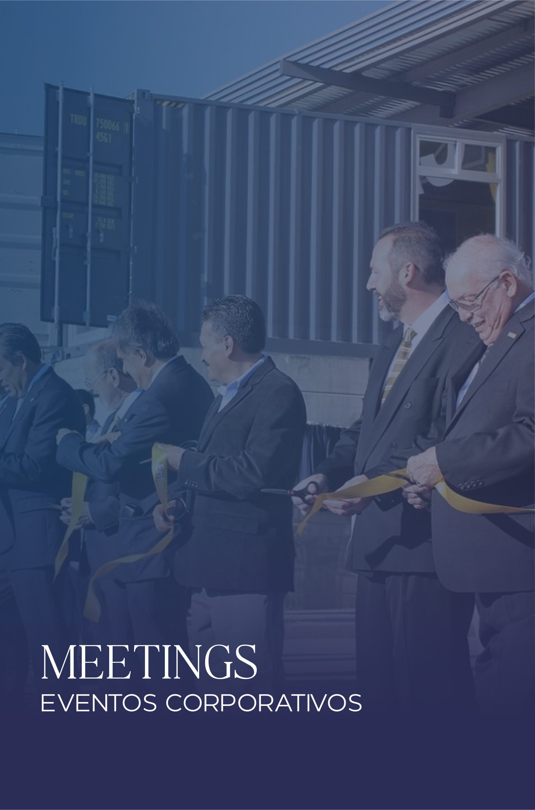 People in business suits participating in a ribbon-cutting ceremony outdoors at a corporate event.