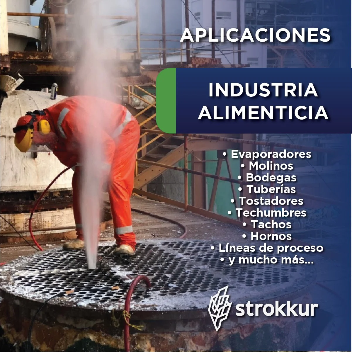 A worker in orange protective gear and yellow ear protection is cleaning a large industrial pipe with a high-pressure water jet at an industrial site with scaffolding and metal stairs in the background.