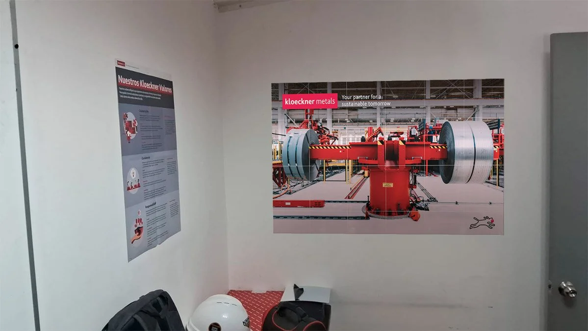 Poster on wall showing industrial machinery with red and gray parts at a factory.