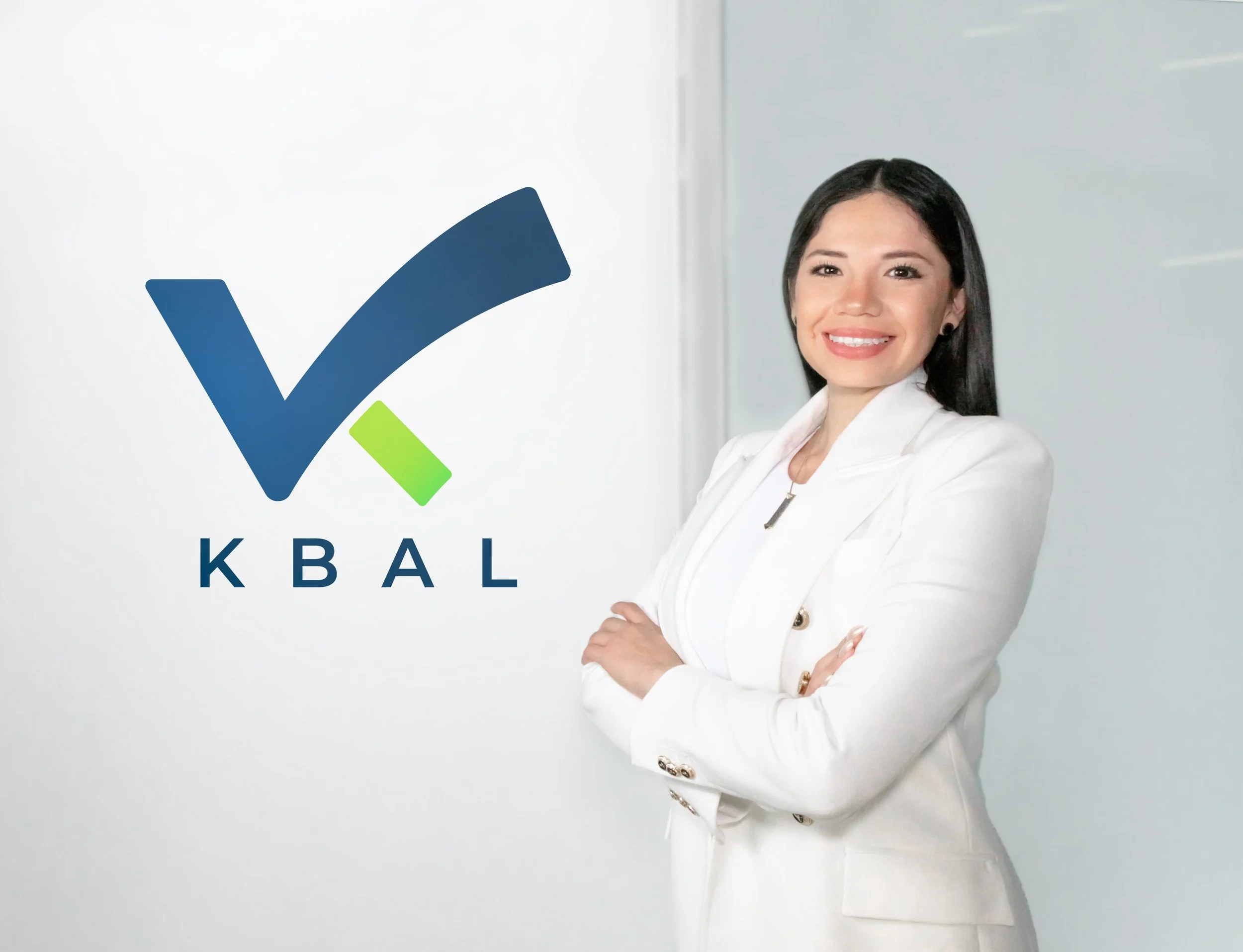 A woman in a white blazer smiling with crossed arms standing next to a logo with a check mark and the letters KBAL.