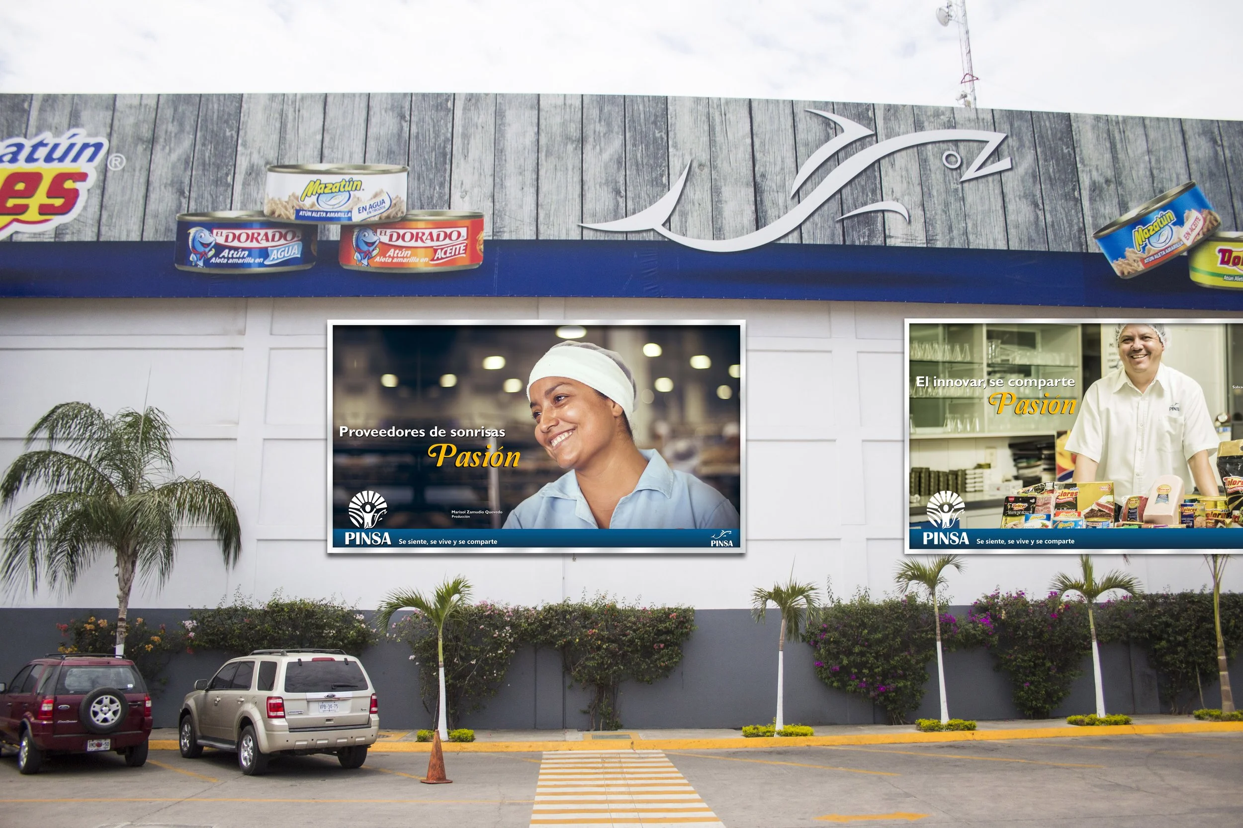 Large building with two digital advertisements, one featuring a smiling woman in a light blue uniform with the text "Proveedores de sonrisas, Pasión" and the other showing a man with a smile with the text "El innovar, se comparte, Pasión". Several ca