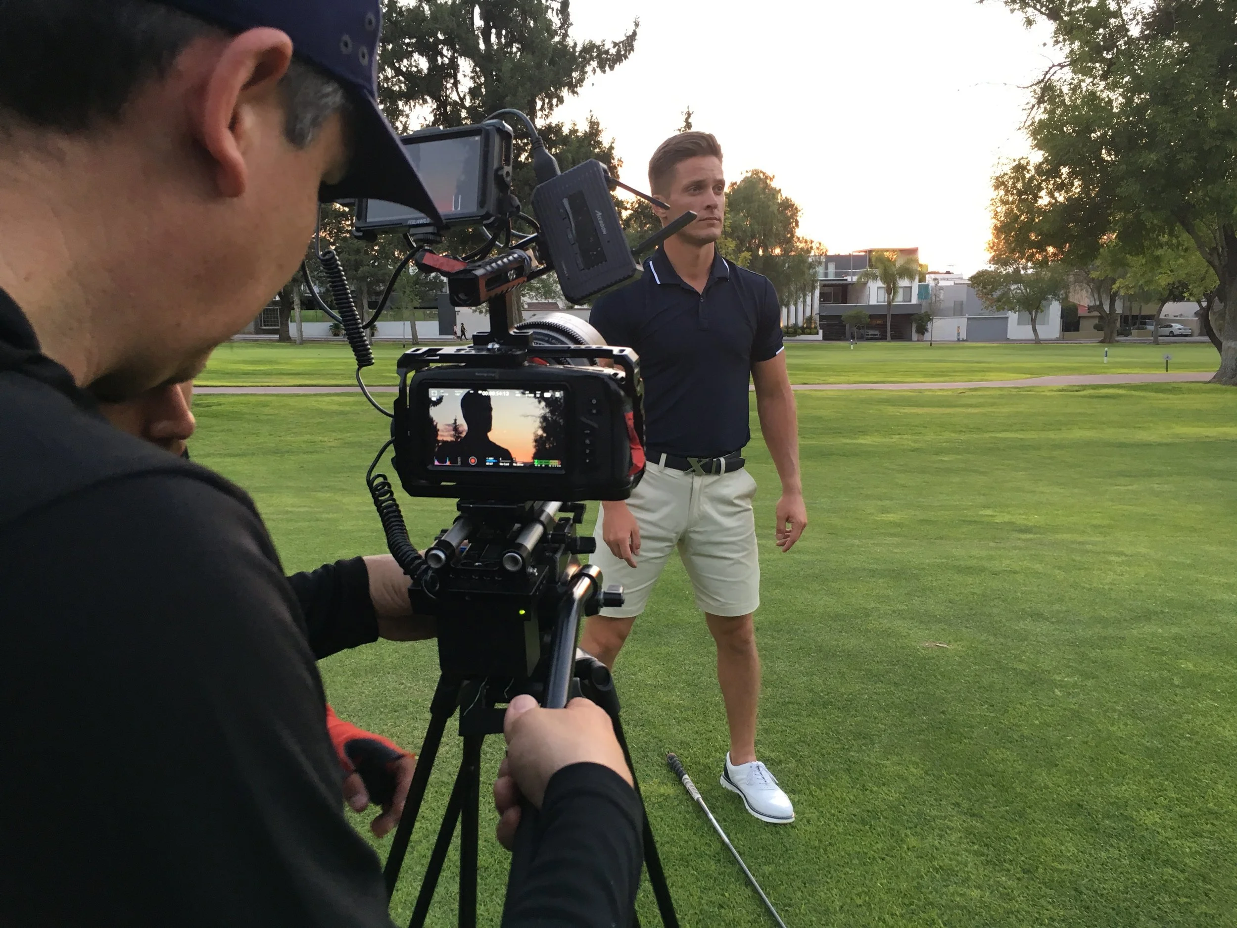 Filmmaker filming of a man on a golf course during sunset.