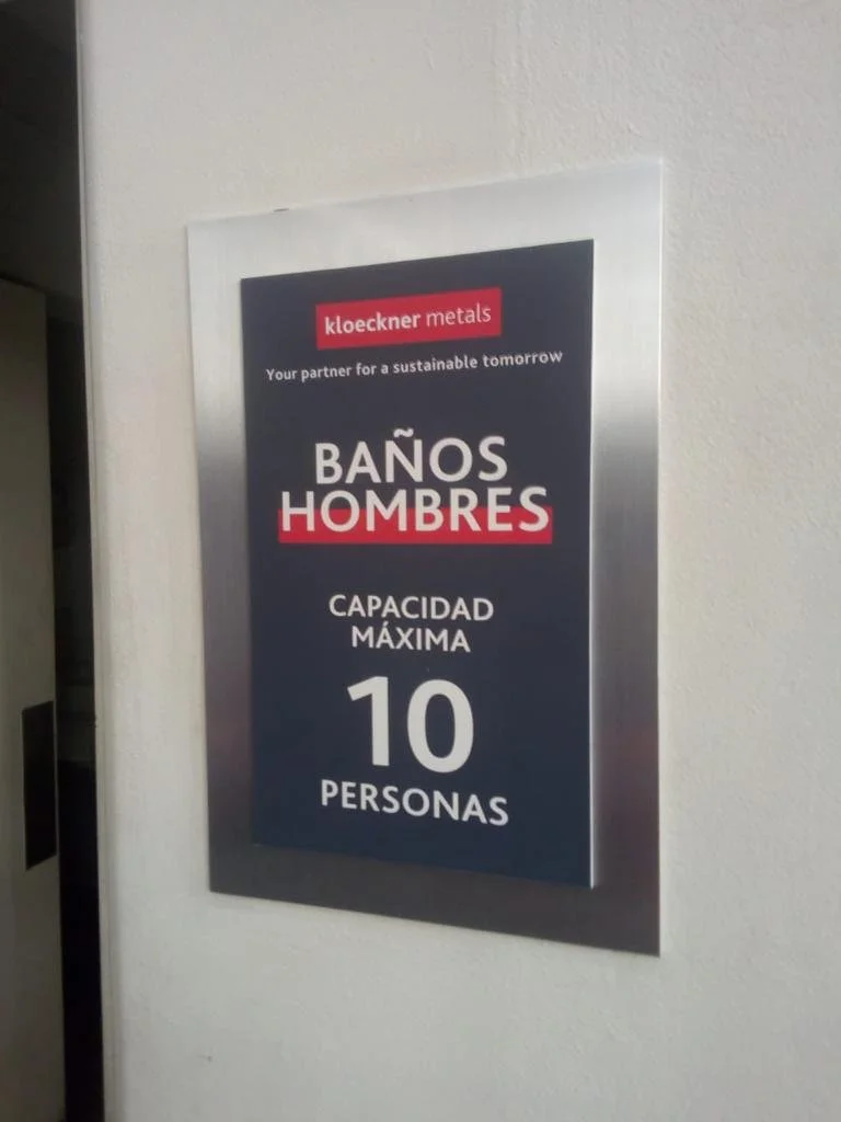 Sign indicating restroom capacity for men, maximum ten people, in Spanish.
