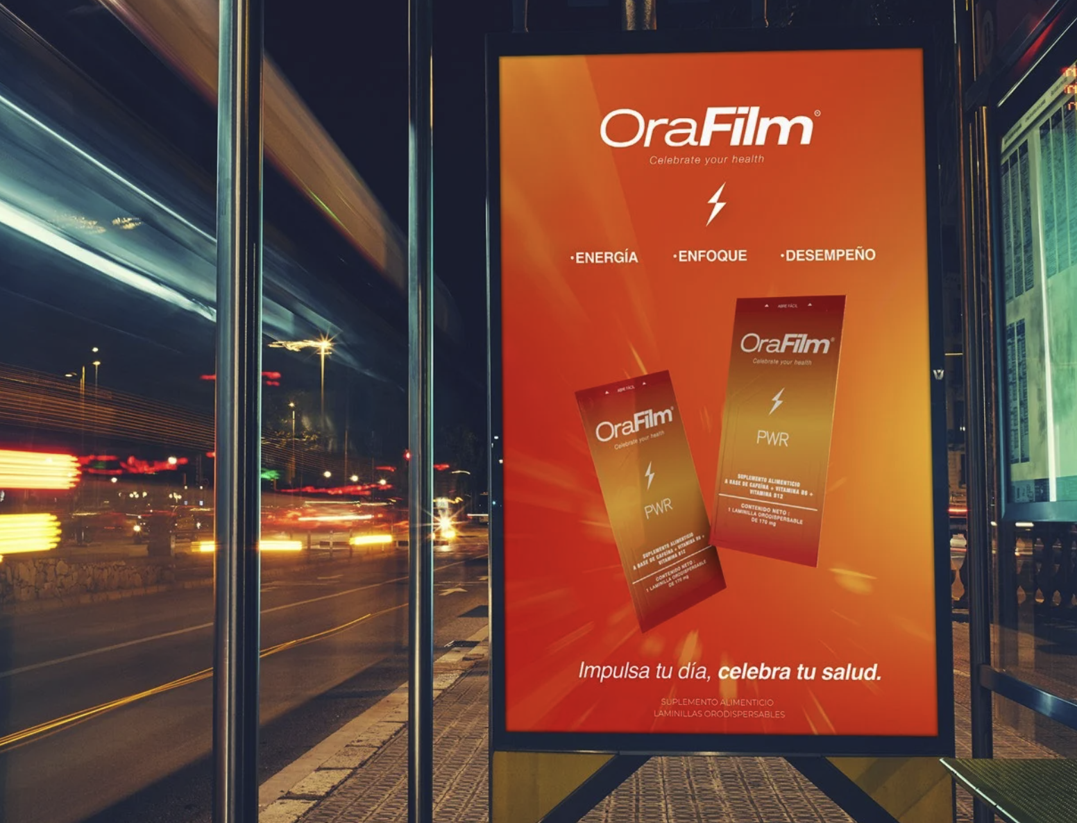 An outdoor bus stop advertisement for OraFilm energy supplements with a bright orange background, featuring two product images and Spanish text promoting health and energy.