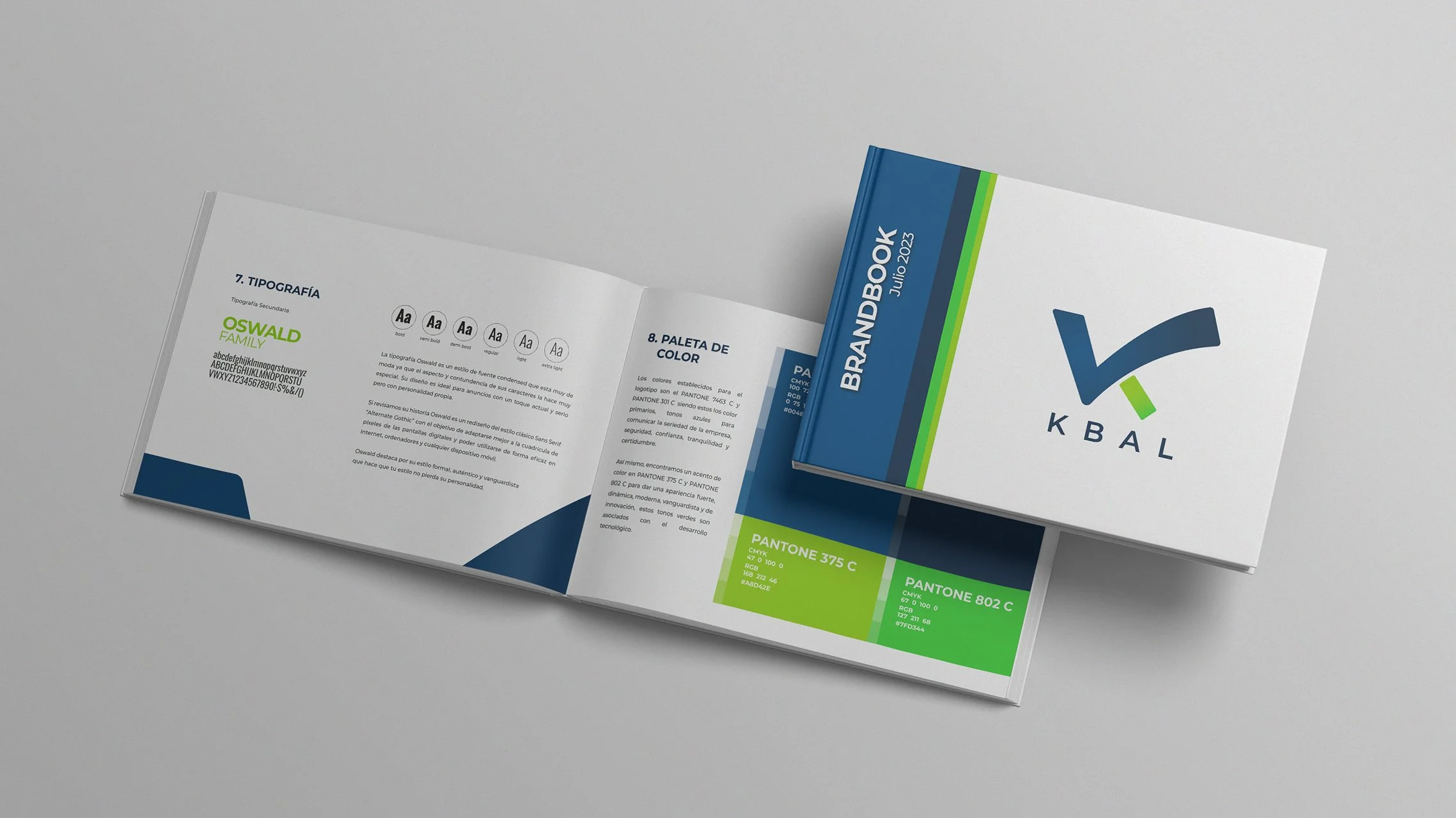 An open brand guidelines booklet displaying typography and color palette sections, with a closed booklet on top that shows a stylized logo and the text "K B A L".
