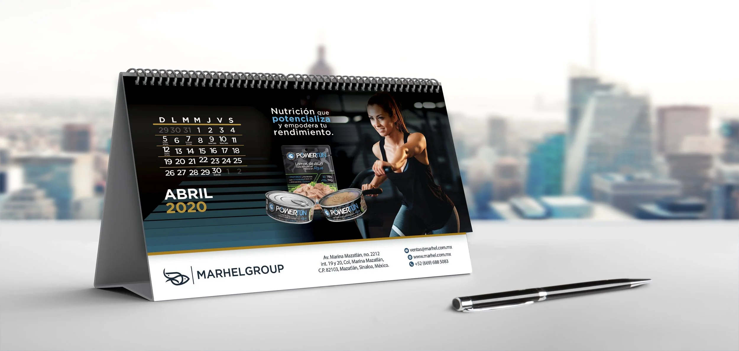 Desk calendar for April 2020 with a woman on an exercise bike, promotional images of canned food, contact information, and a pen on a white surface.