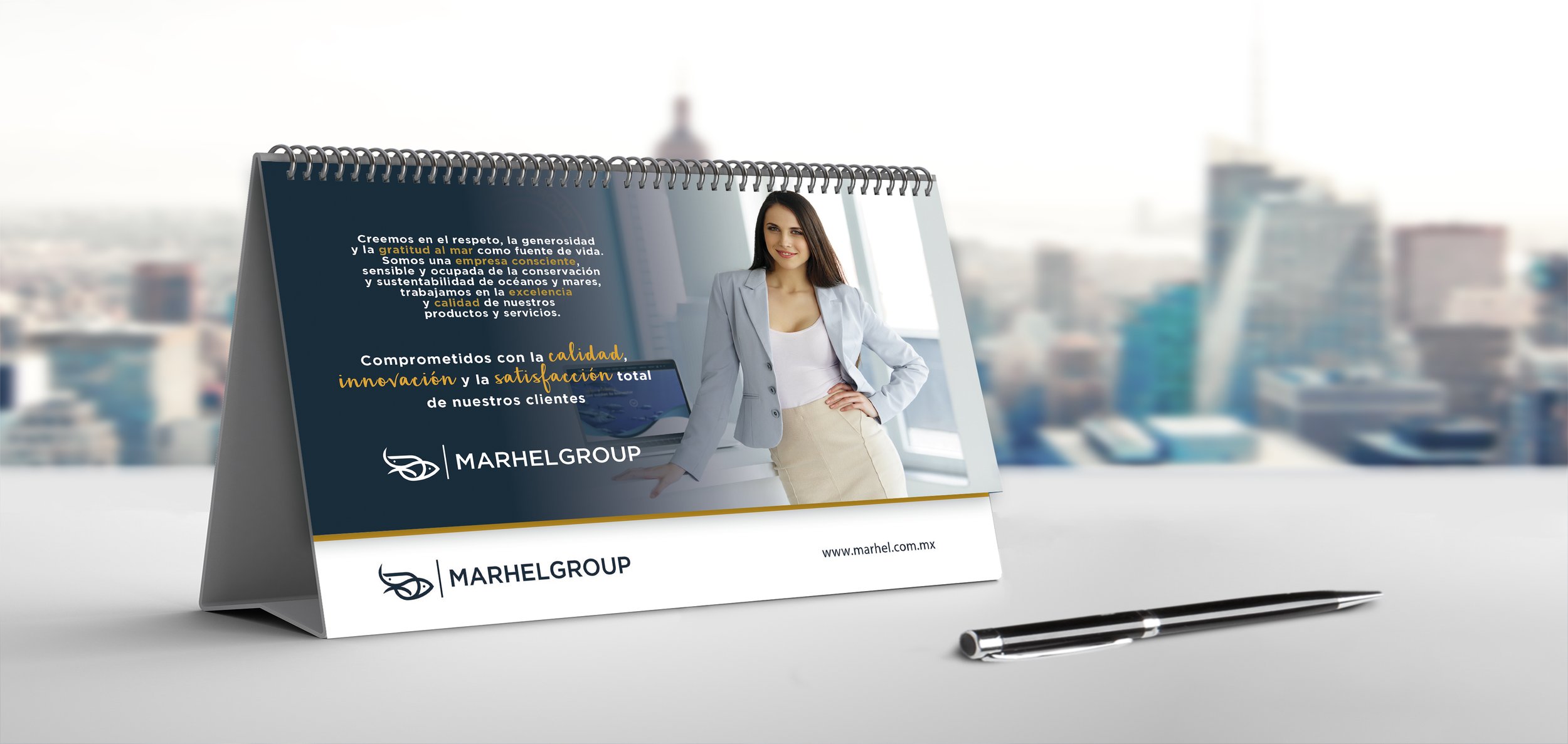 A desk calendar on a white surface displaying an advertisement for Marhel Group with a woman in business attire, and a black pen beside it, against a blurred cityscape background.
