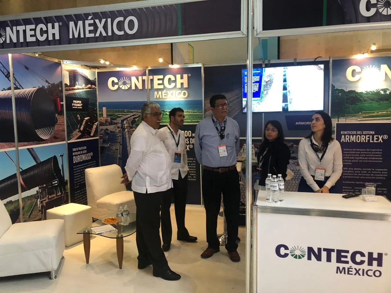 People standing inside a booth at a conference, with banners displaying pipelines, a water treatment system, and the logo 'CONTECH MEXICO'.